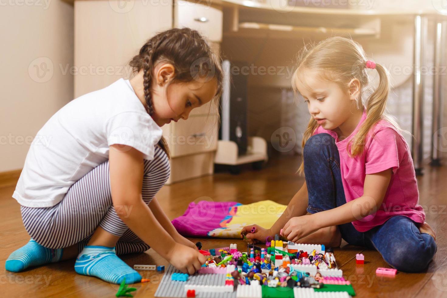 Two cute little children are playing with blocks happy girls at home funny lovely sisters photo