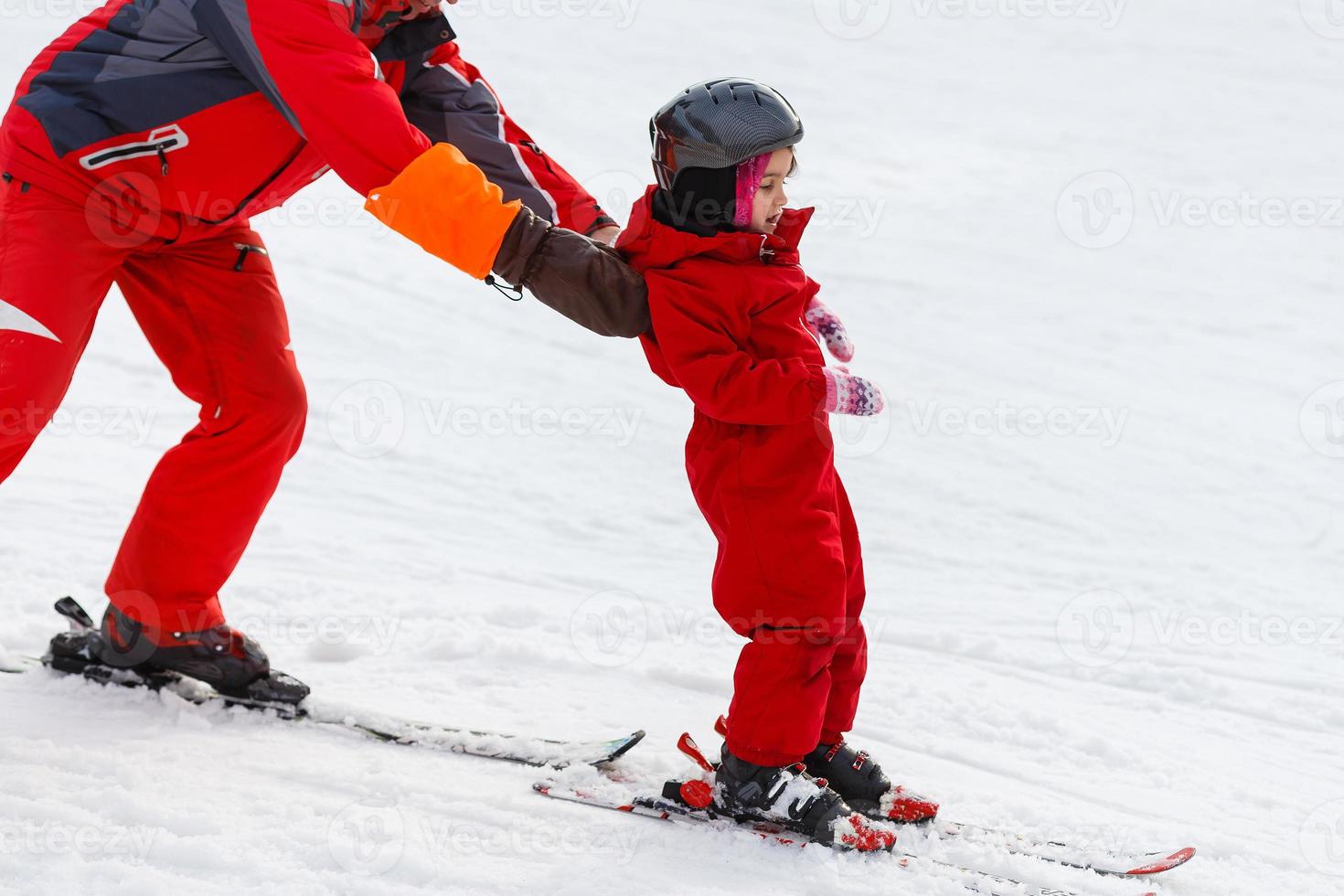 Professional ski instructor is teaching a child to ski on a sunny day on a mountain slope resort with sun and snow. Family and children active vacation. photo