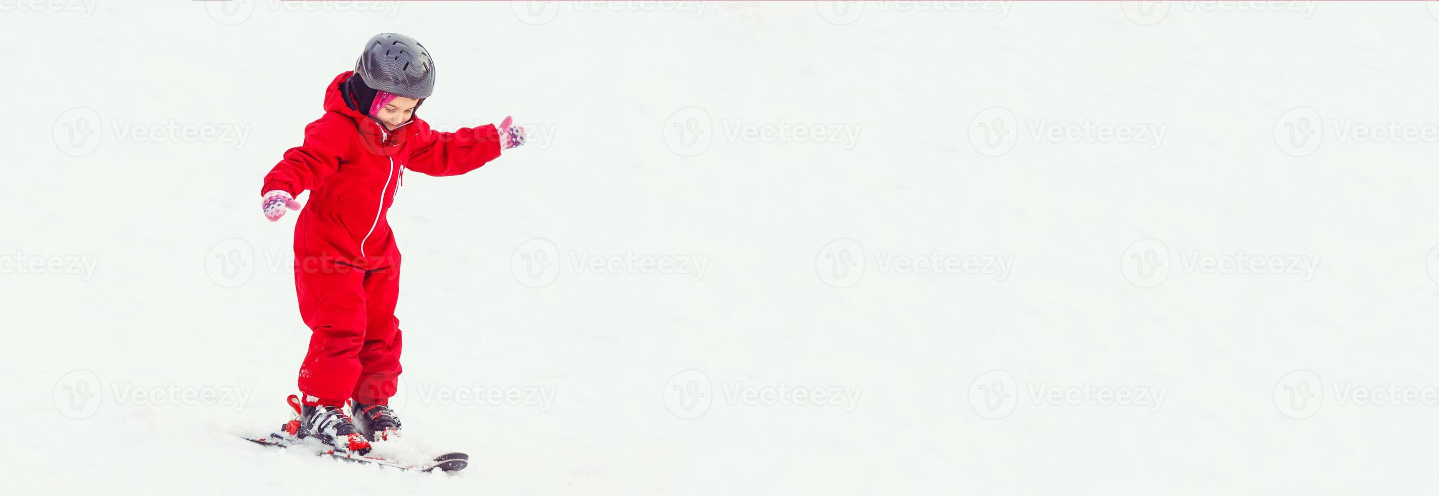 Girl child is learning to ski get up after a fall she slowly slides on skis in soft fresh snow photo