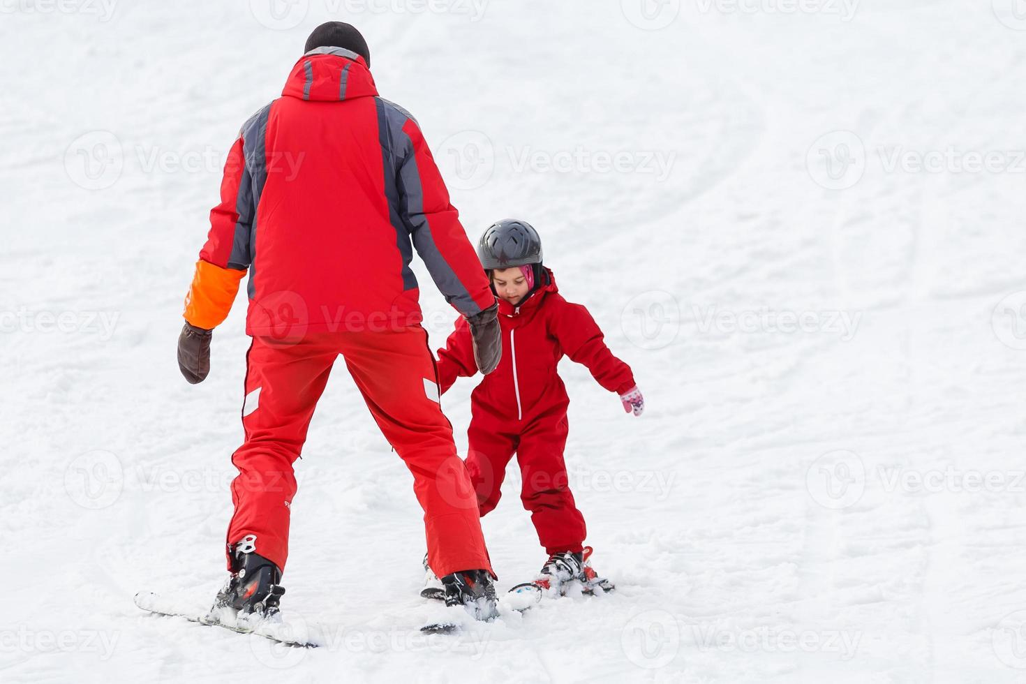 instructor de esquí profesional está enseñando a un niño a esquiar en un día soleado en un complejo de montaña con sol y nieve. familia y niños vacaciones activas. foto