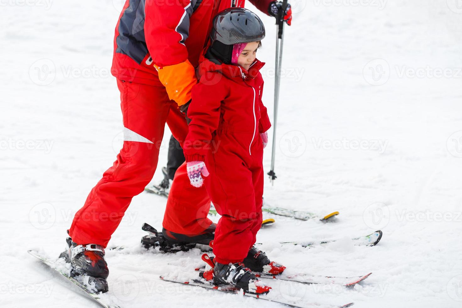 Professional ski instructor is teaching a child to ski on a sunny day on a mountain slope resort with sun and snow. Family and children active vacation. photo