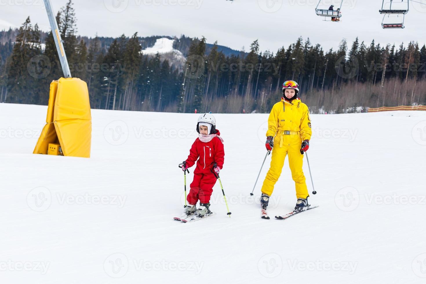 Little girl and a woman are skiing down a mountain photo