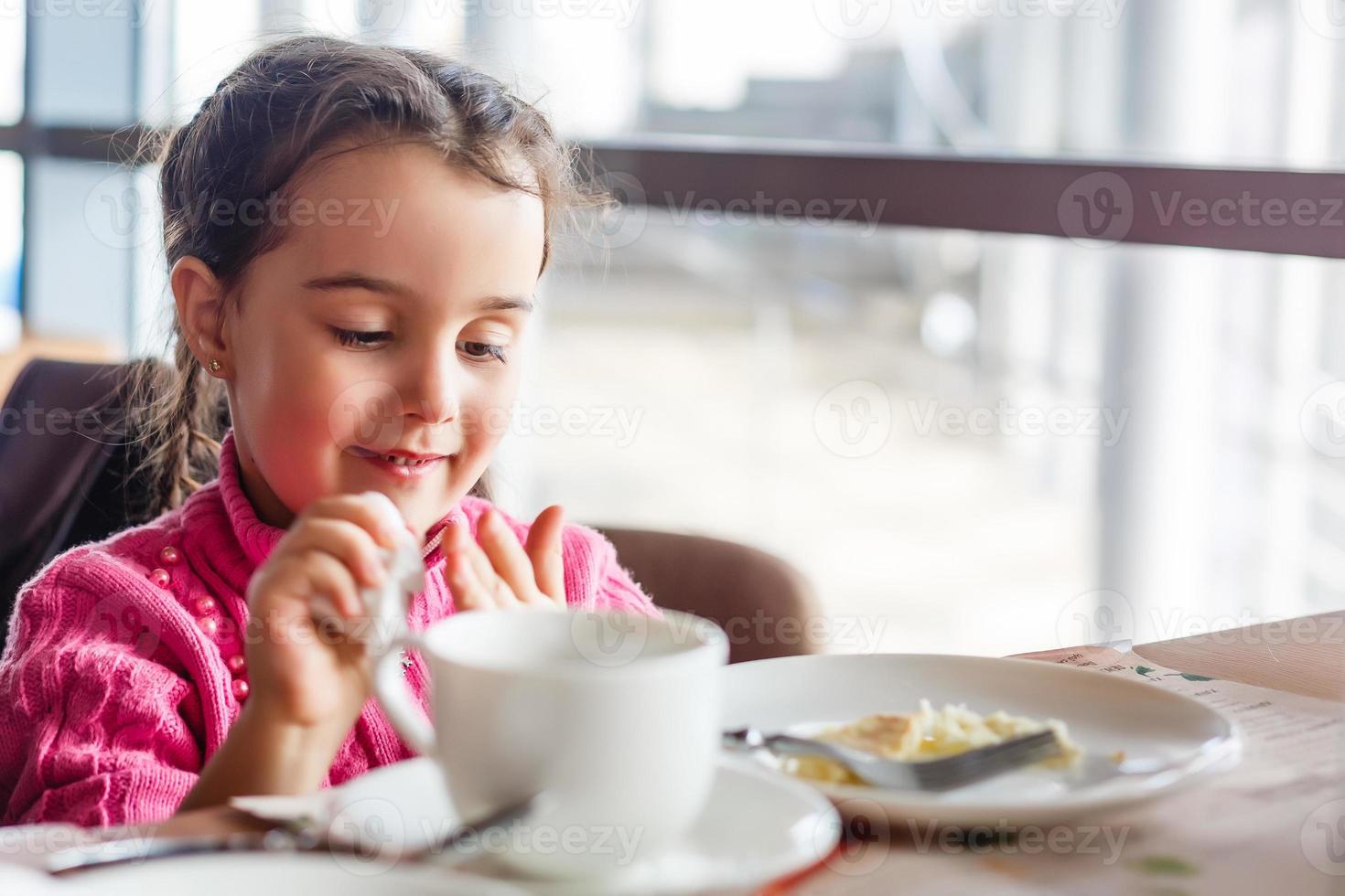 cute little girl drinks tea in the morning photo