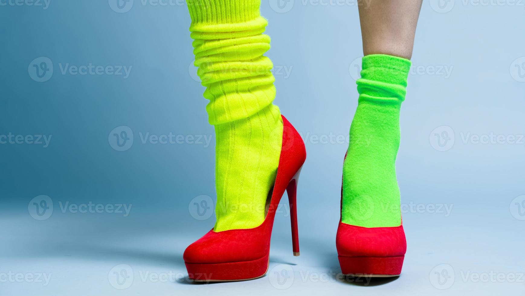 woman with two different sports socks wearing elegant red high hills isolated on blue background photo