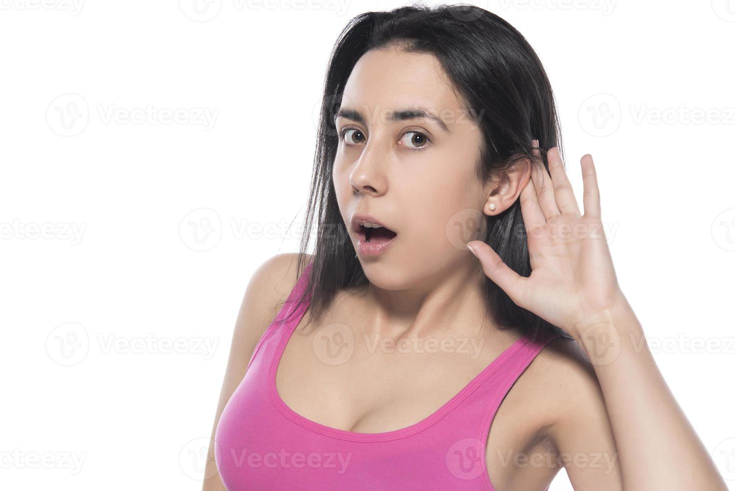 What, say louder, cannot hear you. Confused intense and annoyed woman in pink t-shirt, gesturing palm cluelessly, holding hand near ear photo