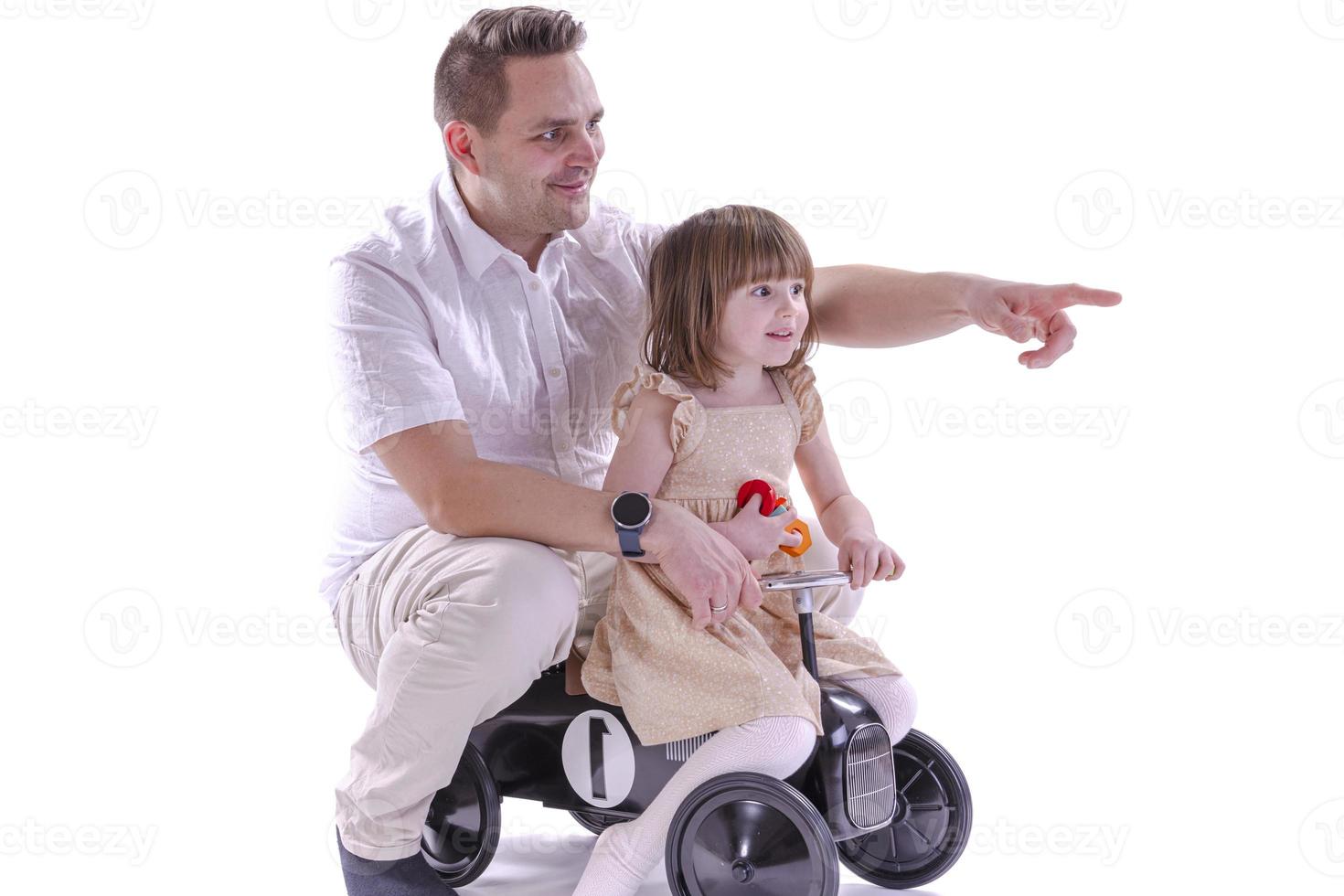 Little girl and her father riding Retro style toy car. photo