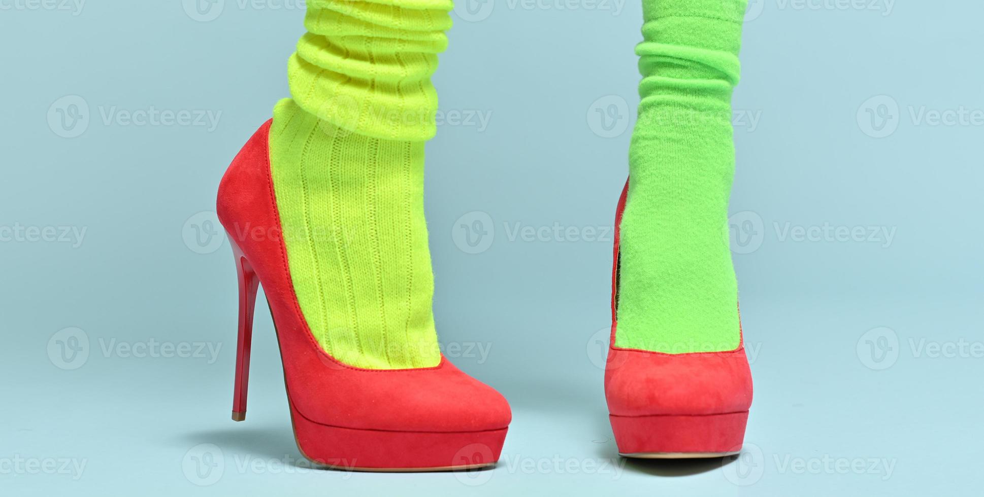 woman with two different sports socks wearing elegant red high hills isolated on blue background photo