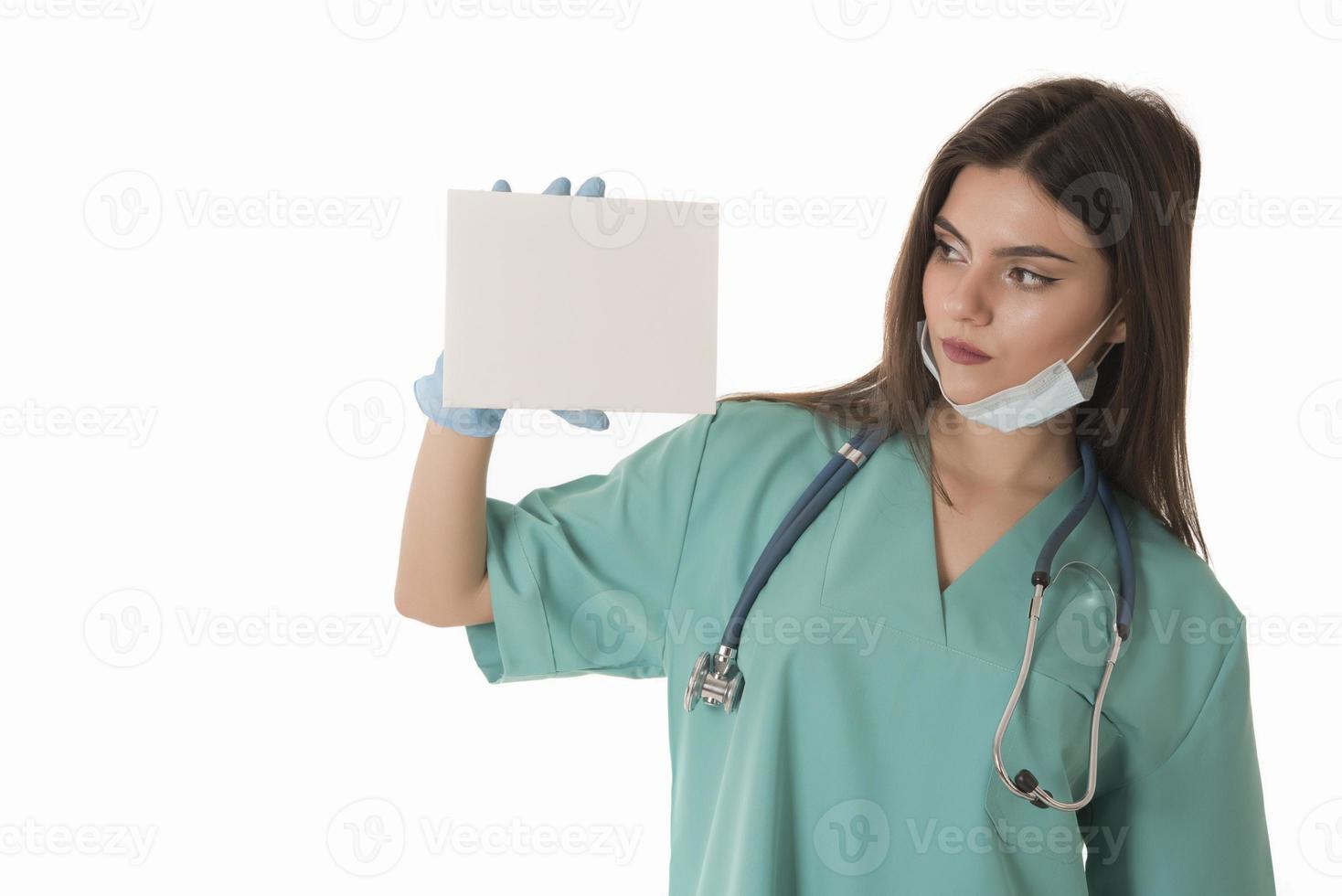 Young smiling woman nurse or doctor in scrubs showing empty blank sign board with copy space photo