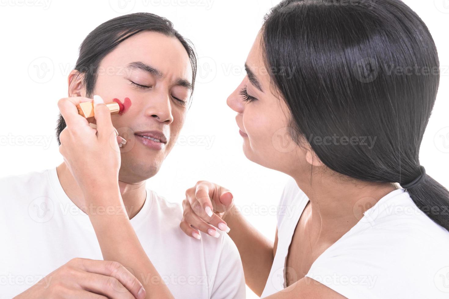 pareja mixta divirtiéndose. modelo femenino árabe dando beso a modelo masculino asiático que ha ahogado bigotes y corazón en su cara. aislado sobre fondo blanco. foto