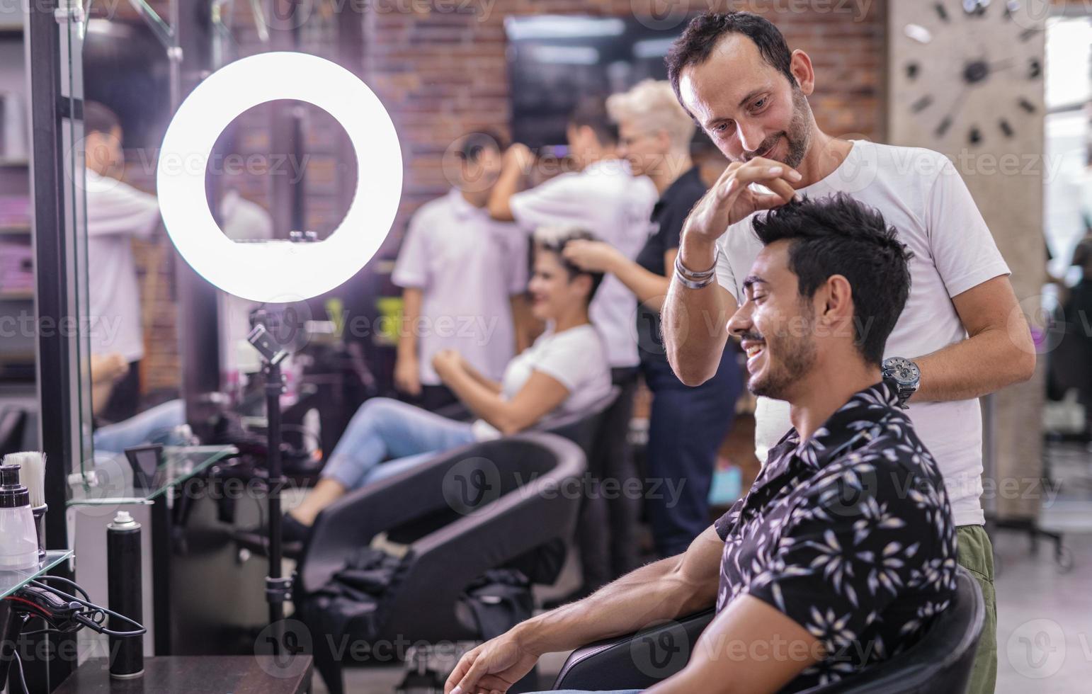 Professional hairdresser is cutting men's hair in beauty salon. photo