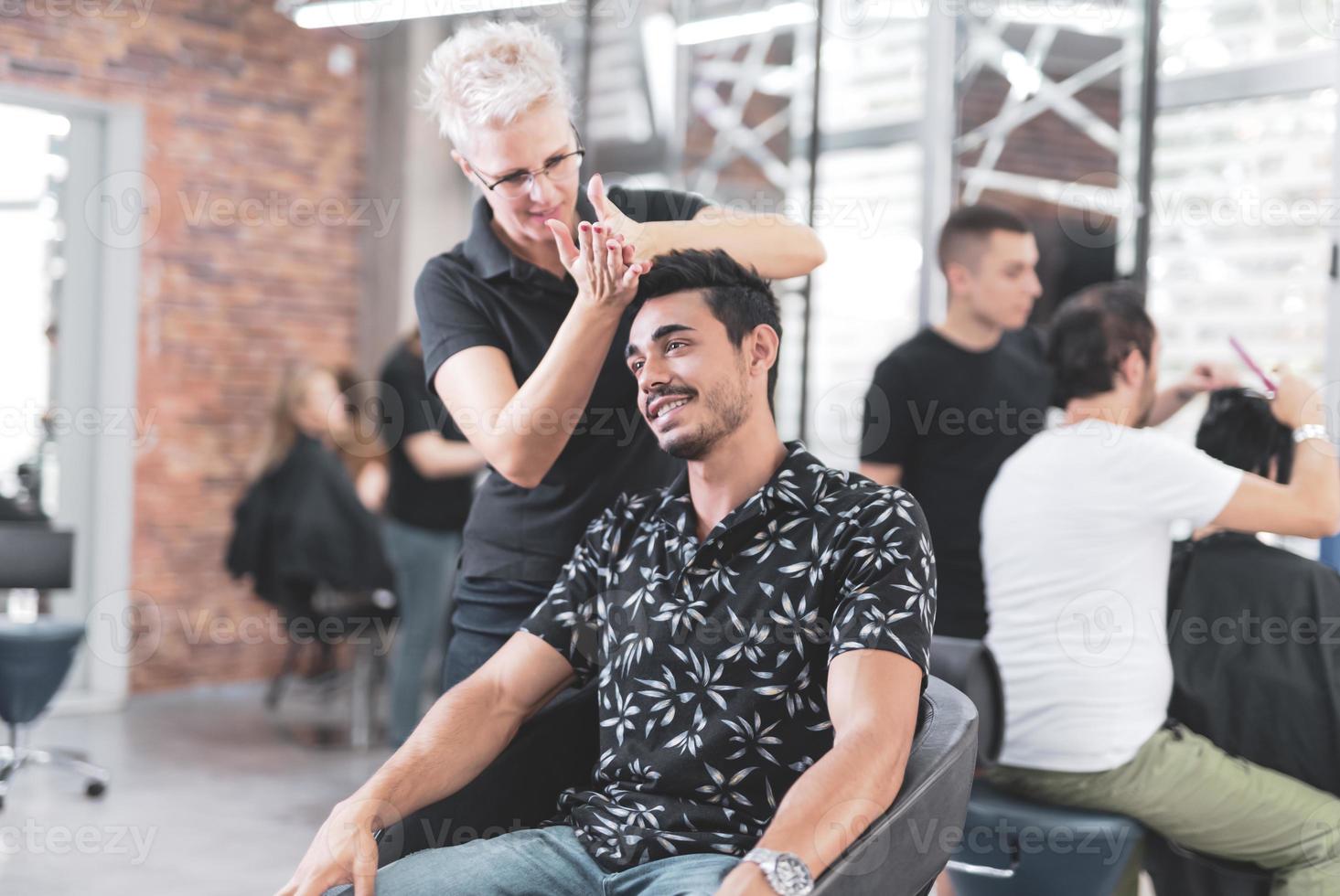 Professional hairdresser is cutting men's hair in beauty salon. photo