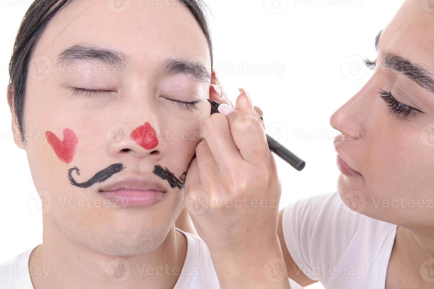 pareja mixta divirtiéndose. modelo femenino árabe y modelo masculino asiático que han ahogado bigotes y corazón en su rostro. aislado sobre fondo blanco. foto