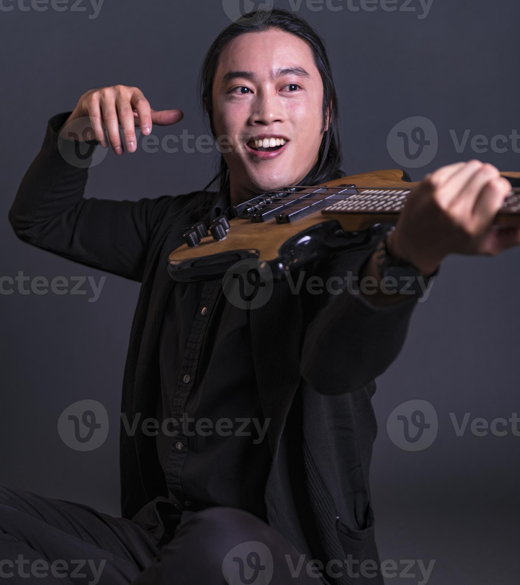 Asian male model playing bass guitar bass guitar as violin. isolated on