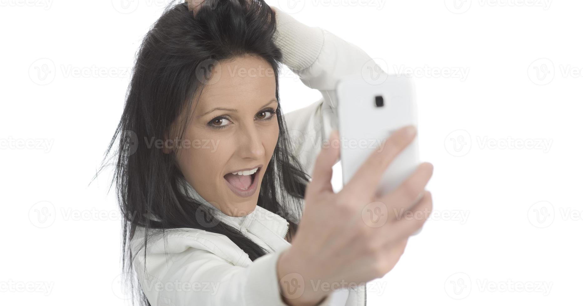 Image of beautiful brunette woman laughing while taking selfie photo on cellphone