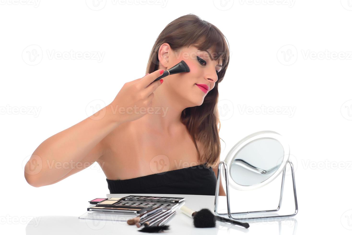 maquillaje diario. mujer joven sonriente aplicando rubor con pincel de maquillaje foto