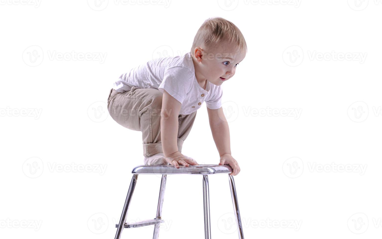 niño sube a una silla de escalera. el comienzo de un concepto de carrera. niño divertido aislado sobre fondo blanco. foto