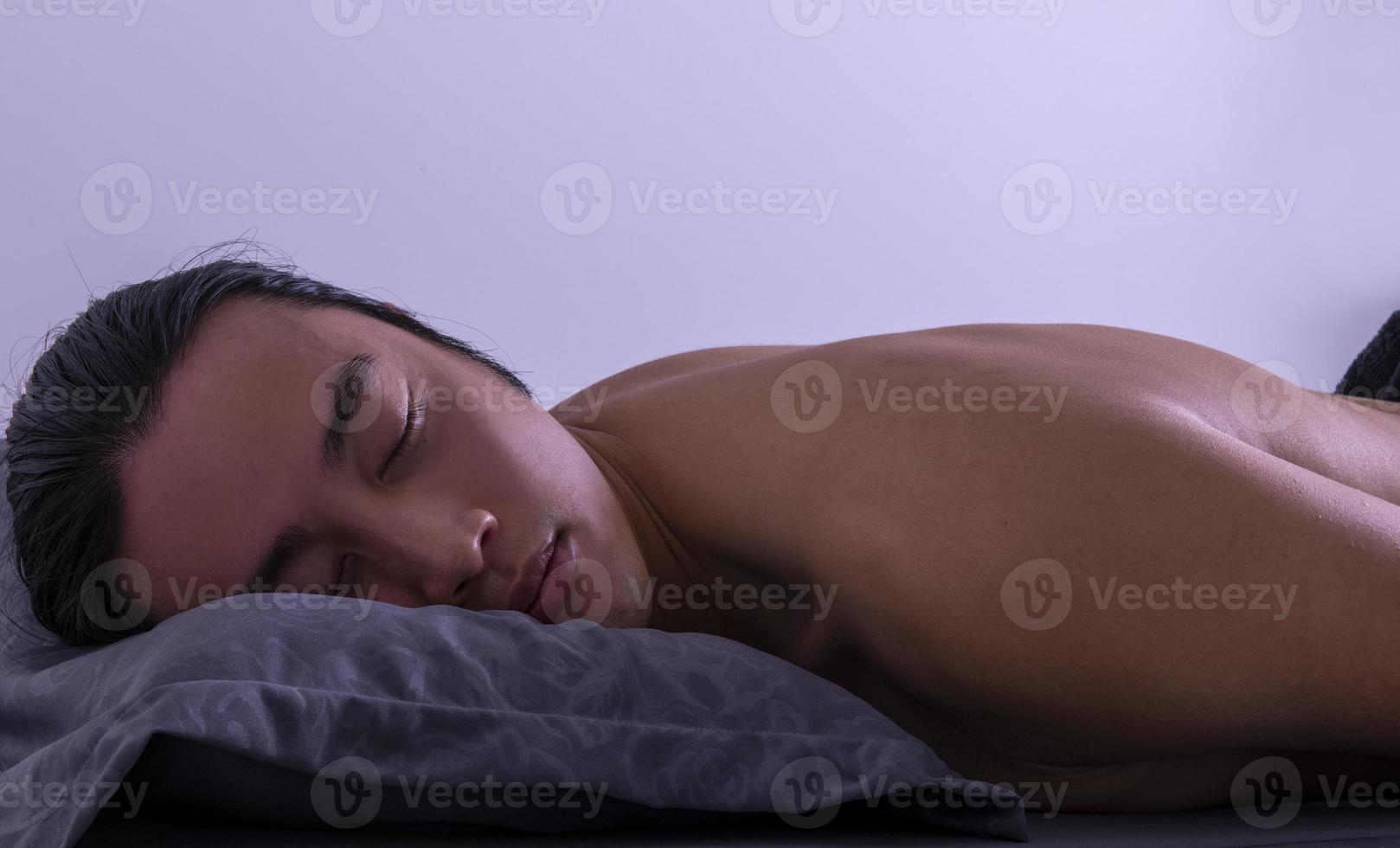 el hombre asiático está durmiendo y teniendo buenos sueños. descansar después del trabajo agotador en el dormitorio en casa foto