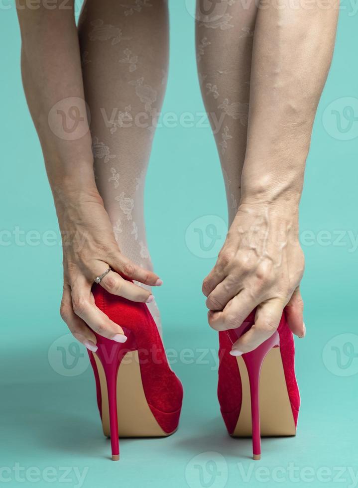 Female feet and heels, woman's lags get tied of shoes with high hill, woman after party, closeup photo