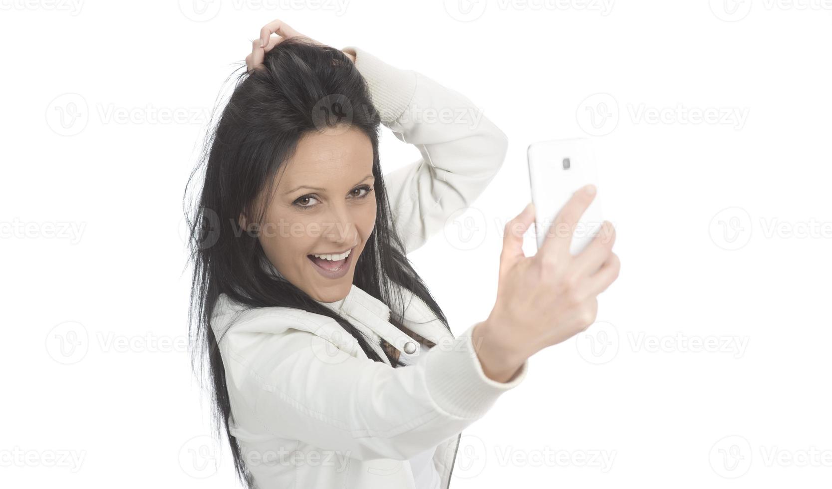 Image of beautiful brunette woman laughing while taking selfie photo on cellphone