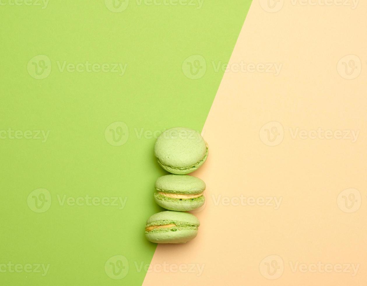 baked green macarons cookies lie in a row on a green beige background photo