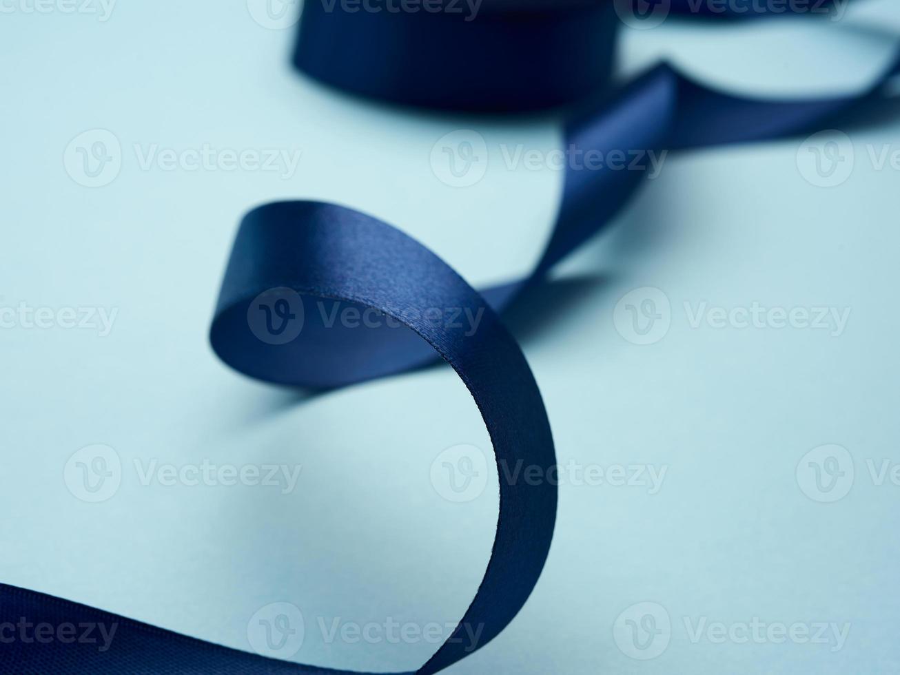 curled dark blue silk ribbon on light blue background photo