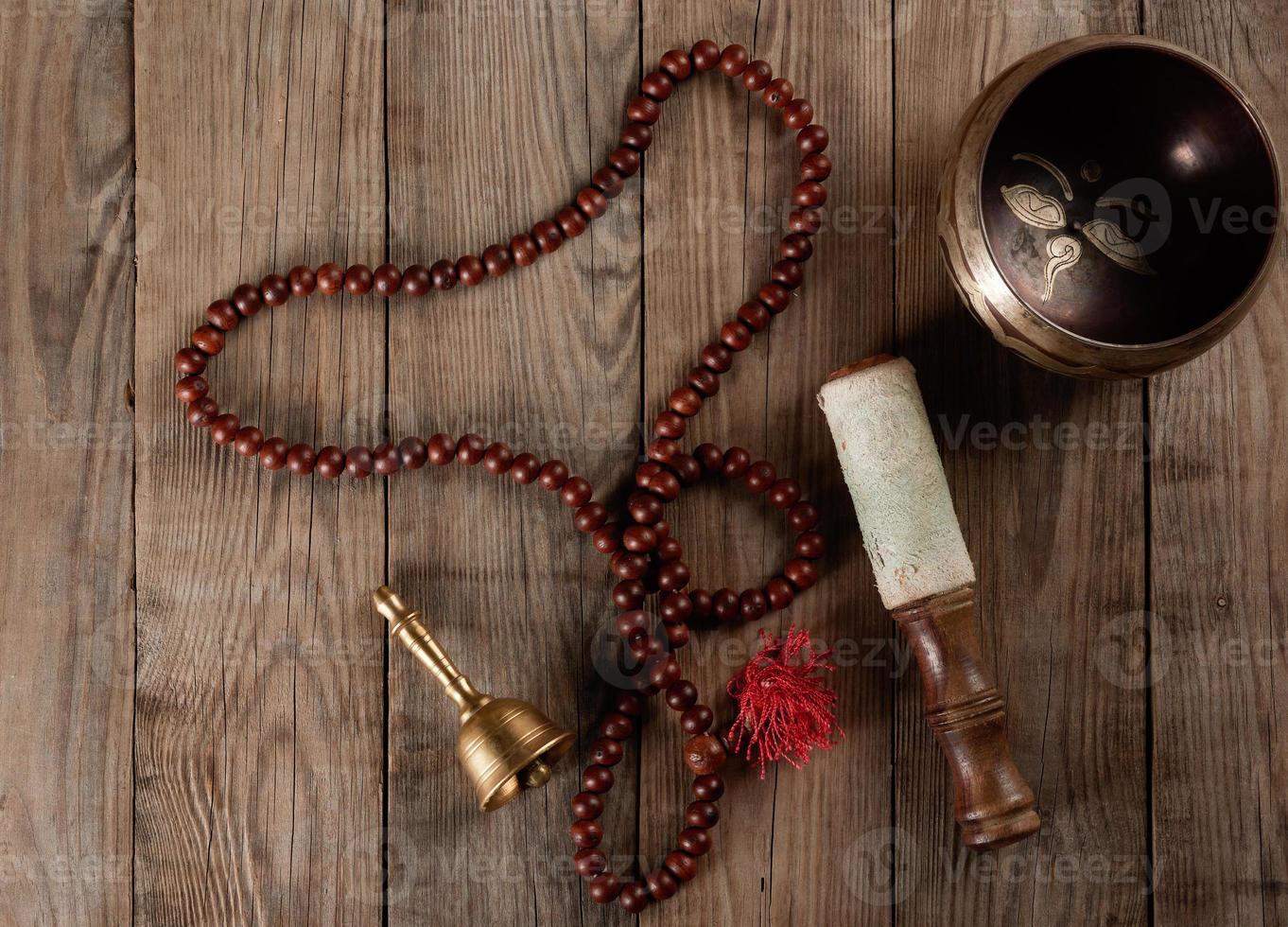 Tibetan singing copper bowl with a wooden clapper on a brown wooden table, objects for meditation and alternative medicine photo