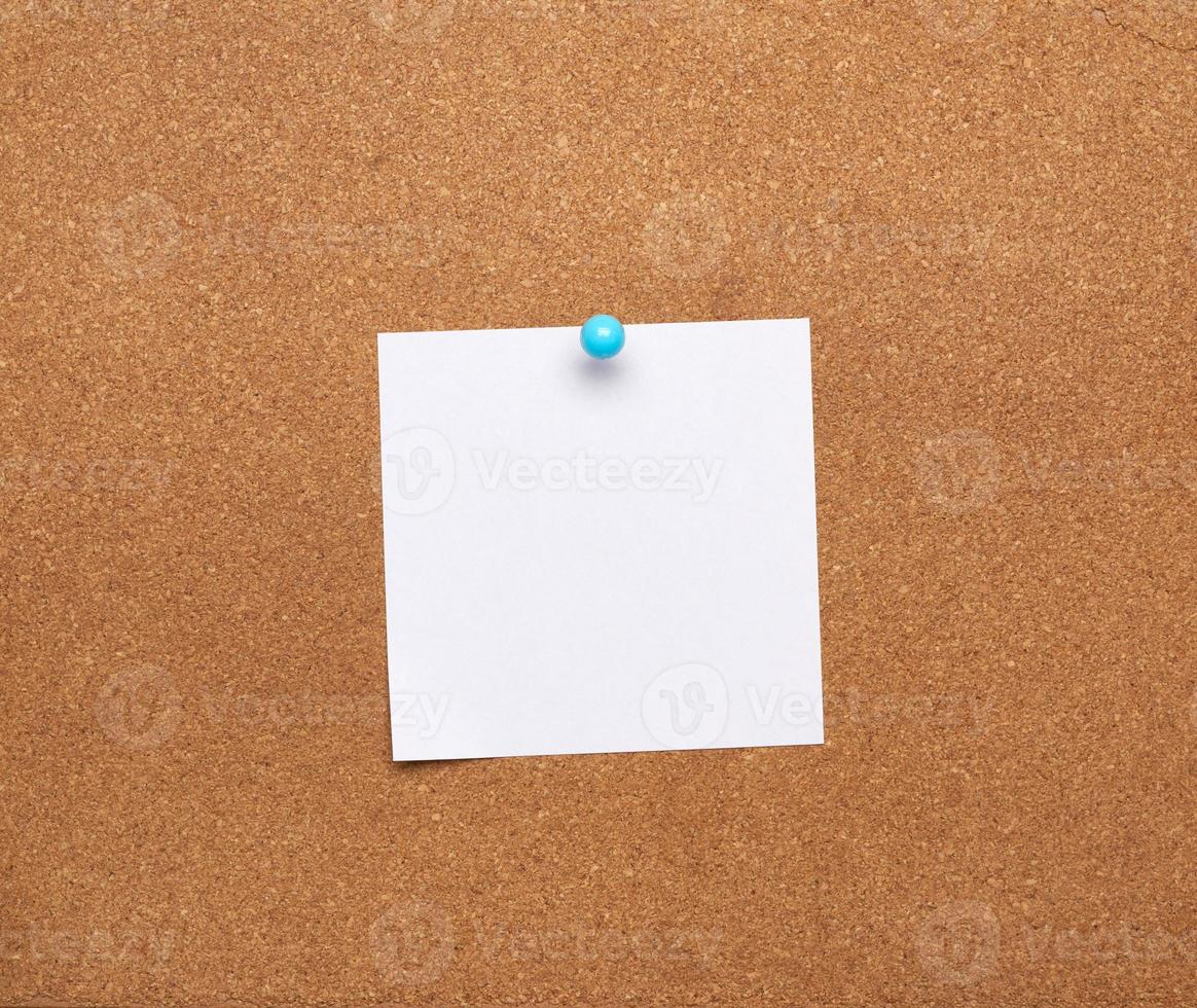 blank square white sheet of paper attached with blue button on a brown background photo