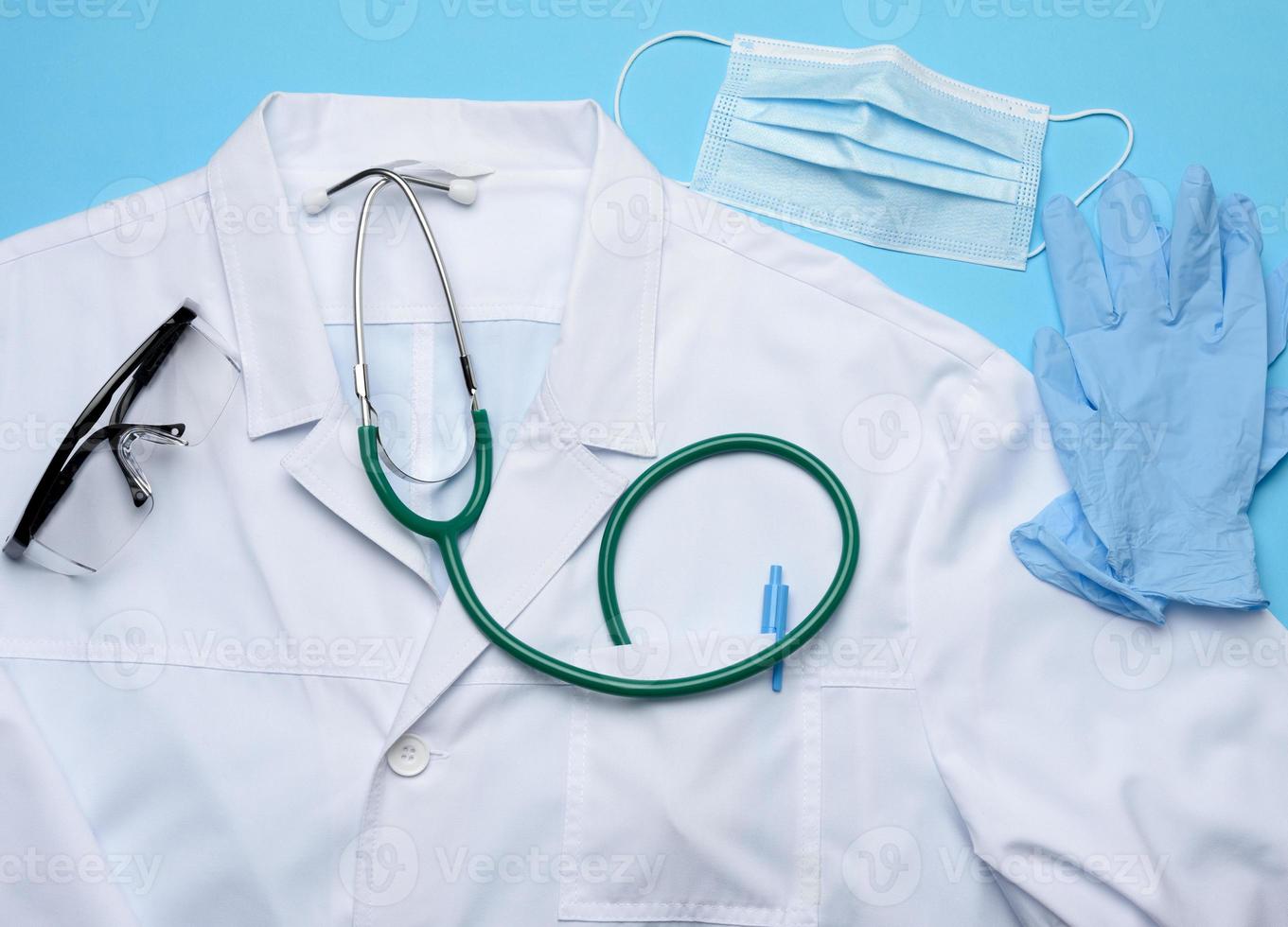white medical gown, disposable mask and protective plastic glasses on a blue background photo