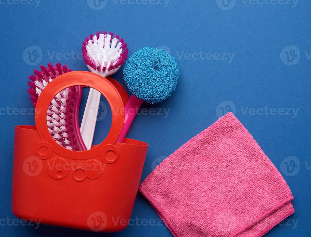 pink basket with washing sponges, brushes on a blue background photo