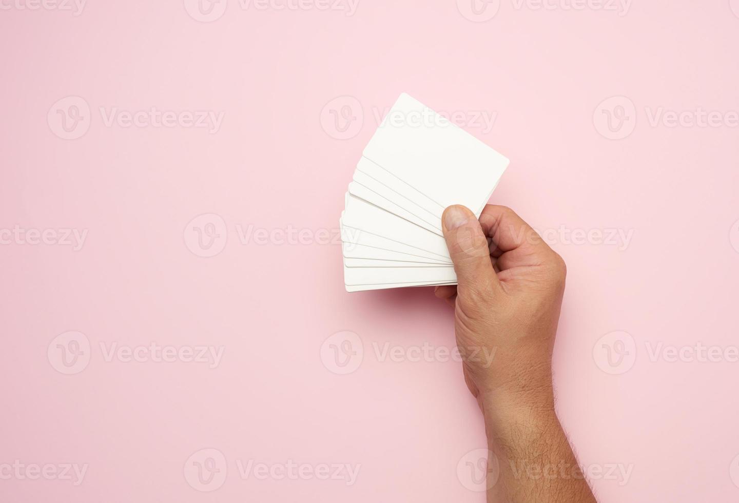 male hand holding a stack of blank white business cards photo