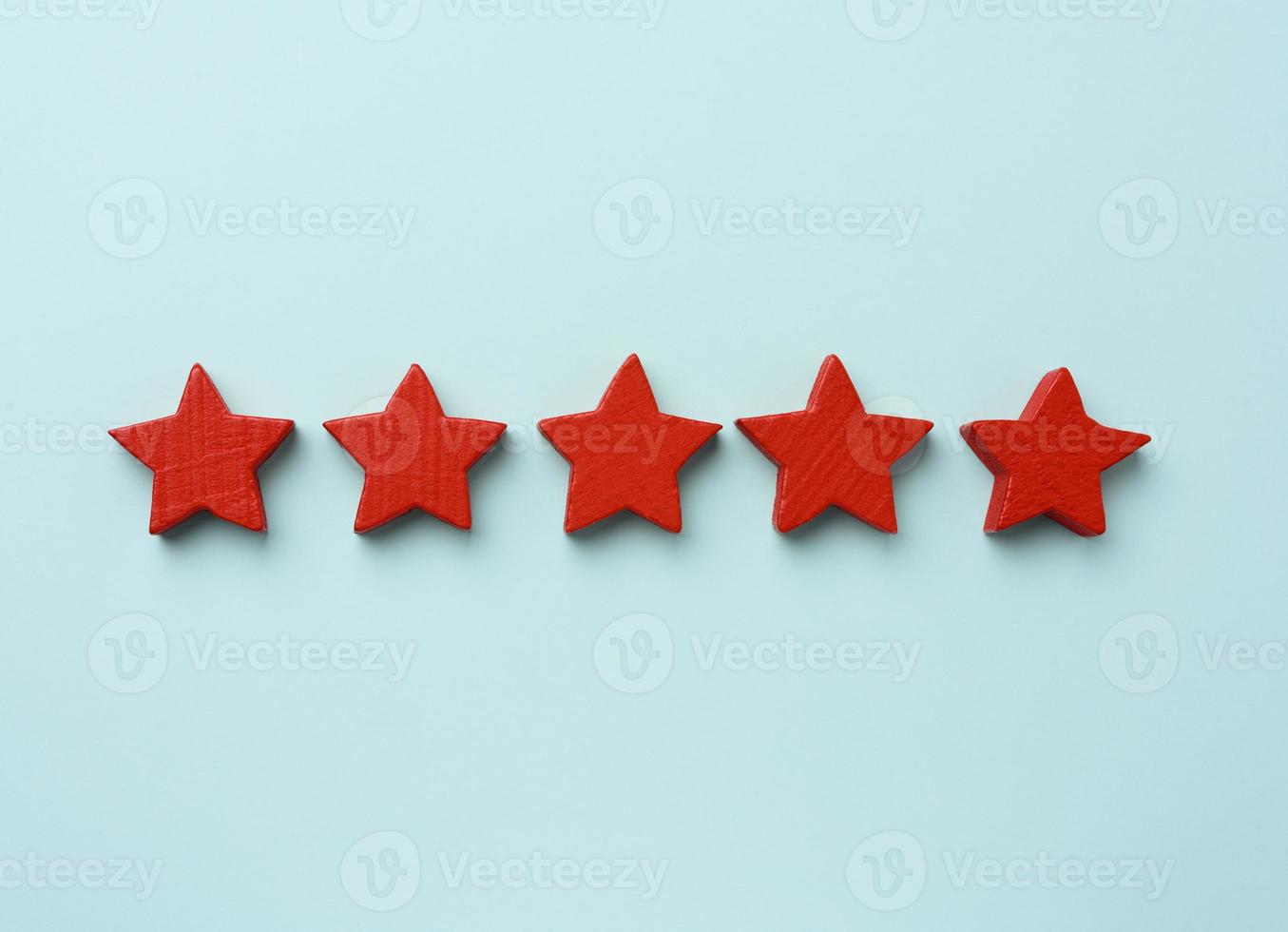 cinco estrellas rojas de madera sobre un fondo azul, puntaje alto foto