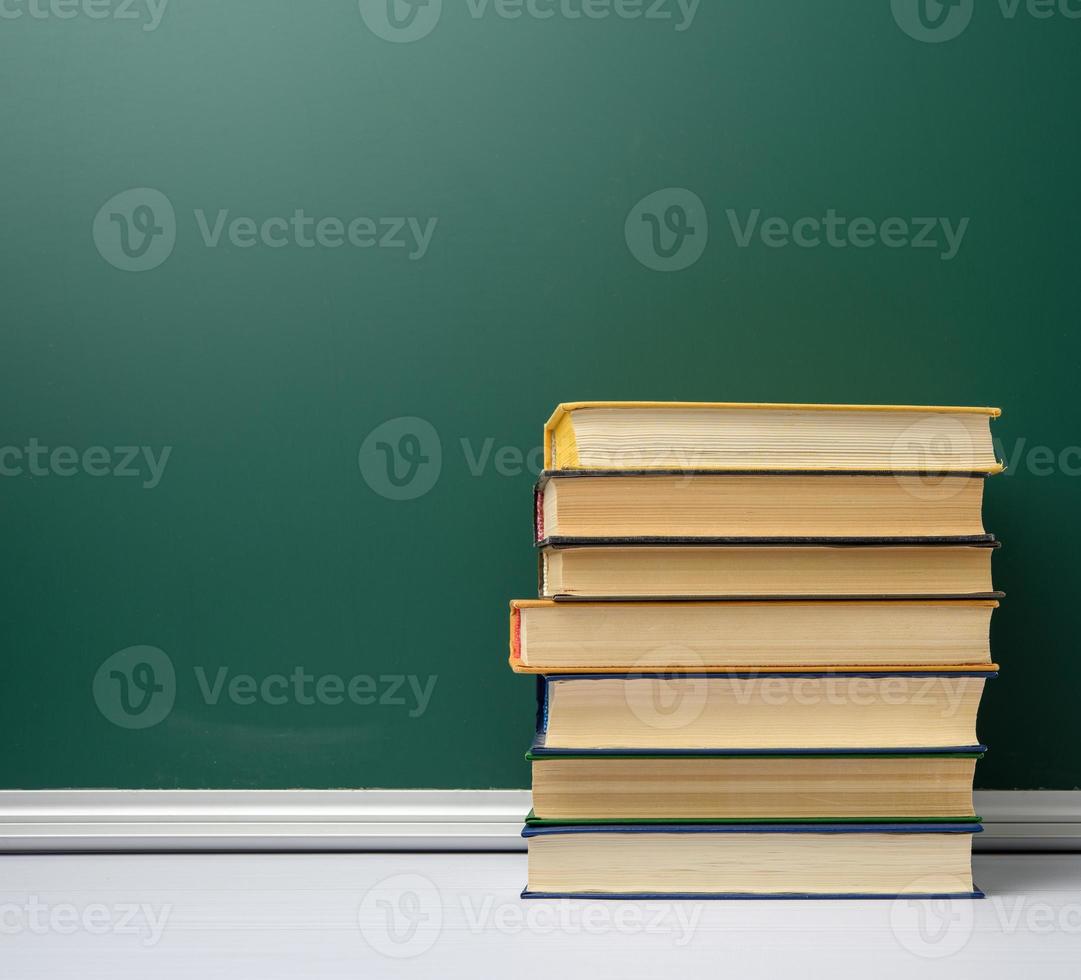 tablero escolar de tiza verde en blanco y pila de libros, regreso a la escuela foto
