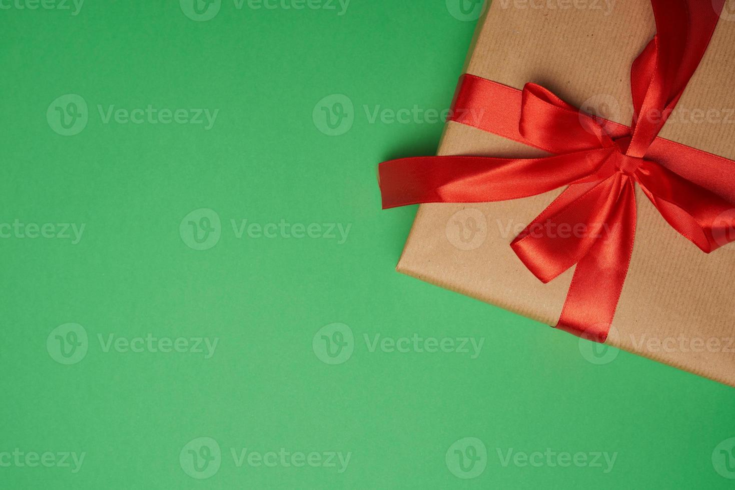 rectangular box wrapped in brown paper and tied with a silk red ribbon with a bow photo
