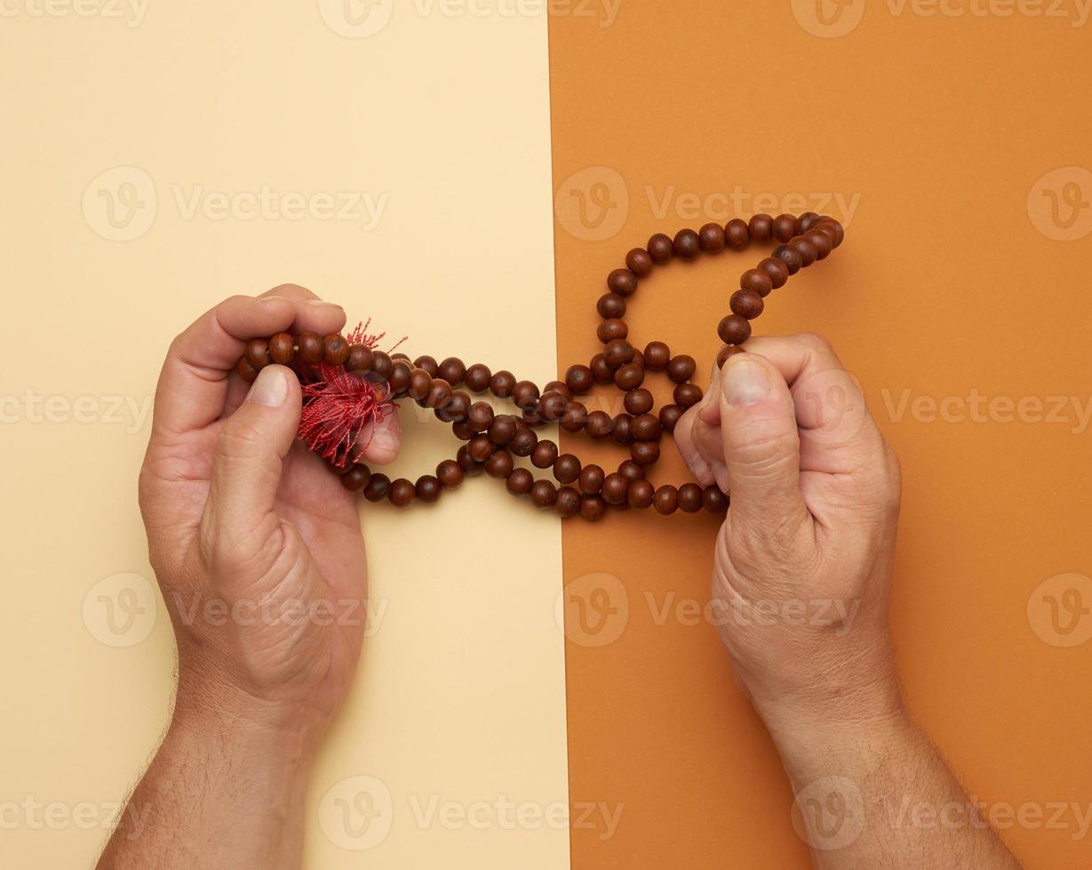 two male hands hold wooden prayer beads photo