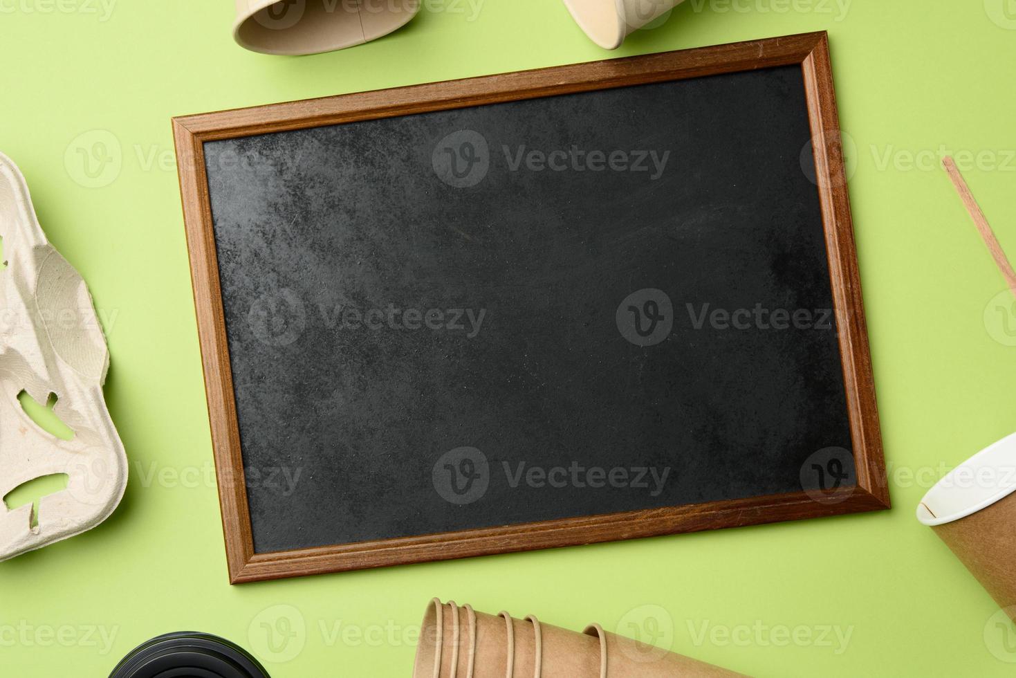 wooden frame and disposable paper cups from brown craft paper and recycled paper holders on a green background, top view photo