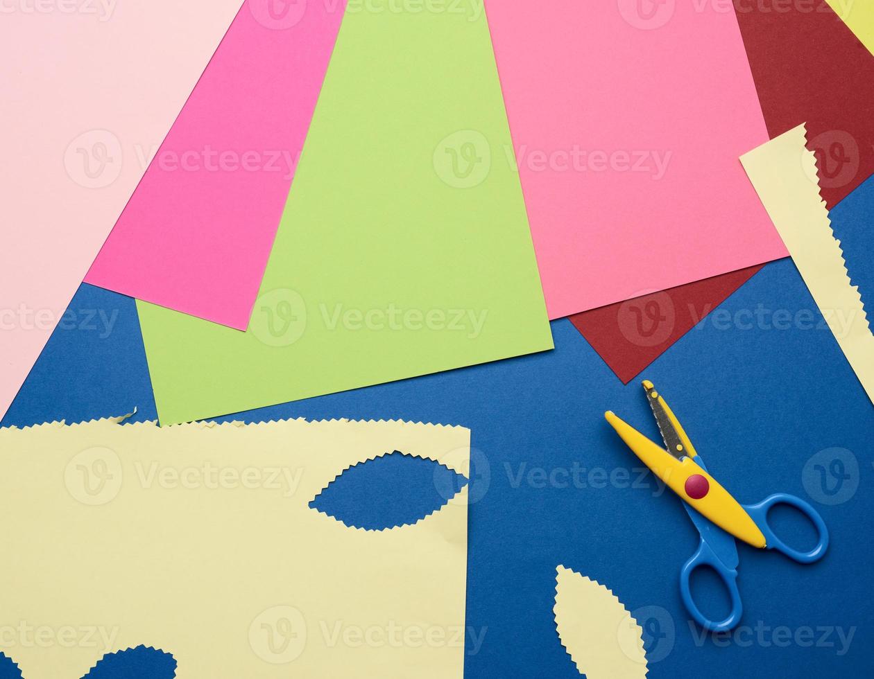 multicolored craft paper and plastic scissors on blue background photo