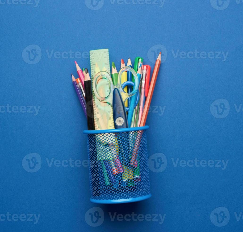 plastic scissors and multicolored wooden pencils on a blue background photo