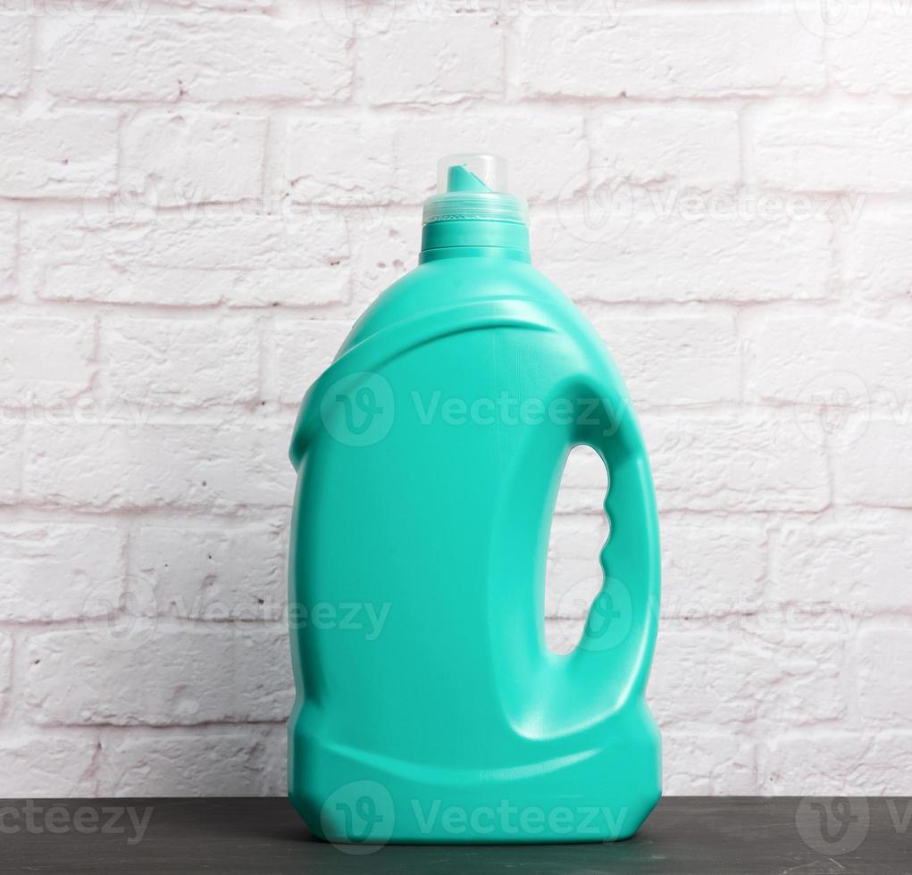 botella de plástico grande con detergente líquido sobre fondo de pared de ladrillo blanco foto