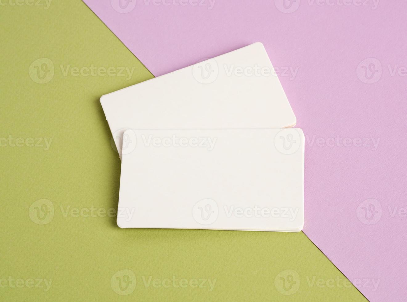 montones de tarjetas de visita en blanco de papel blanco sobre un fondo rosa-verde foto