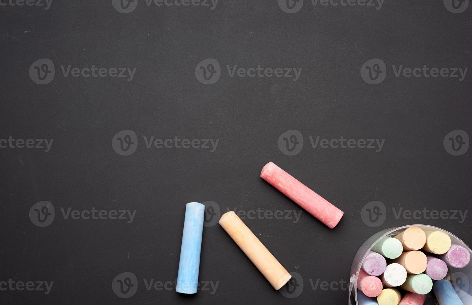 multicolored chalk in a plastic bucket on a black background photo