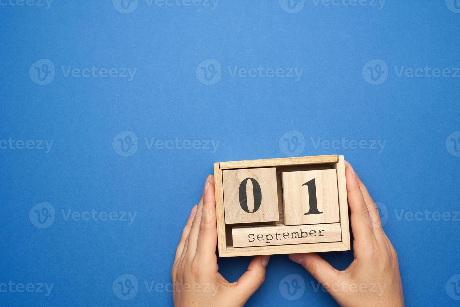 two female hands hold a wooden calendar with the date of September 1 photo