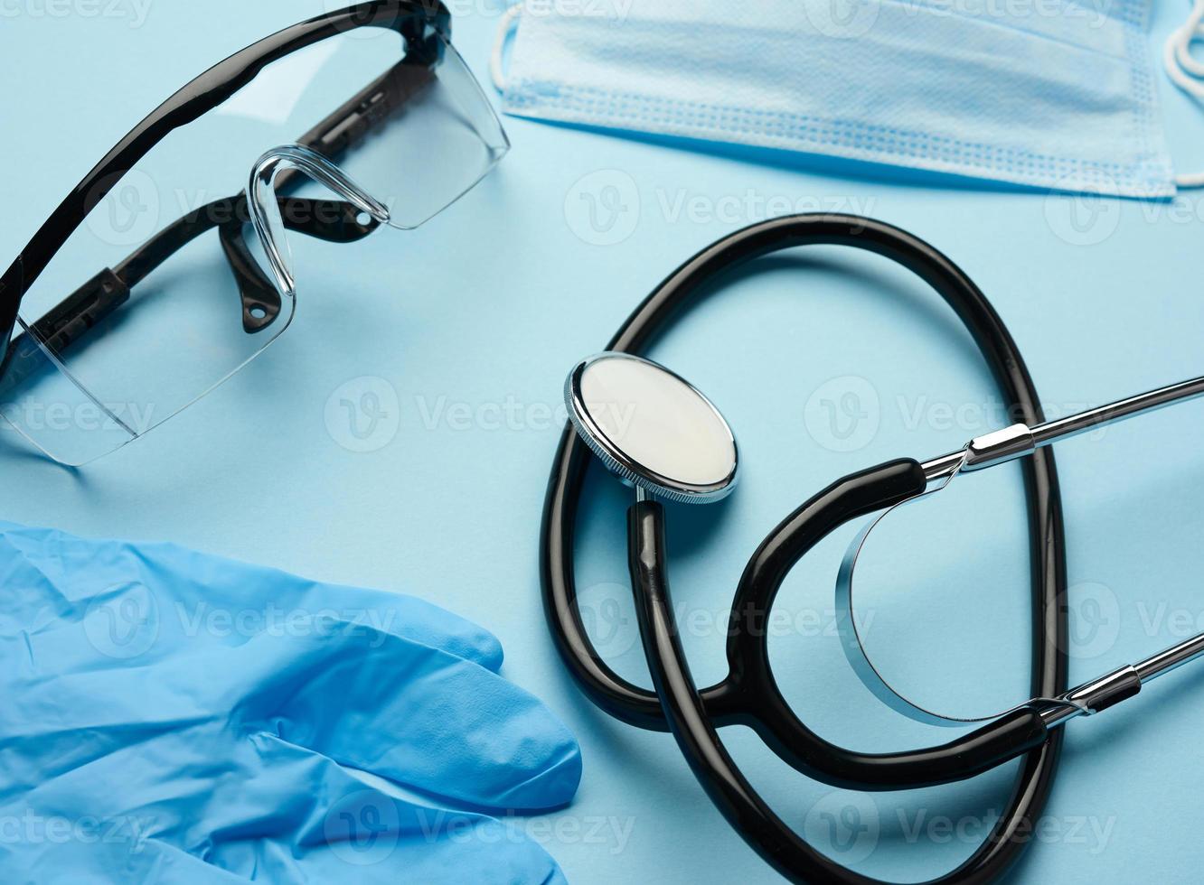 black medical stethoscope, protective plastic glasses and disposable masks photo