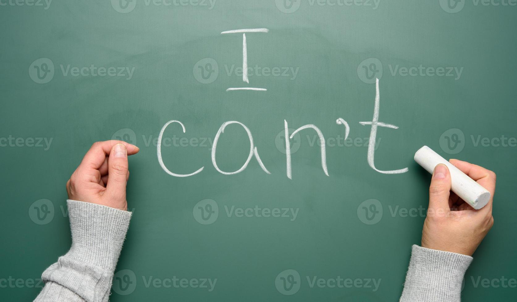 woman's hand writes on a green chalk board with white chalk i cant photo