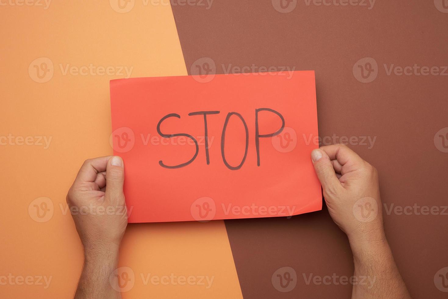 two male hands hold a red sheet with the inscription stop photo