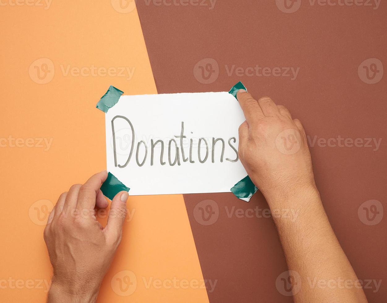 two male hands hold a sheet of paper with the inscription donations photo