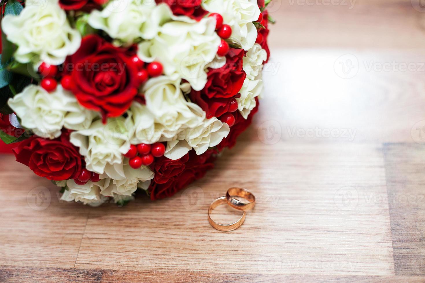 rings and a wedding bouquet of red and white roses on table photo