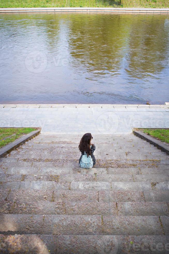 hermosa chica se sienta y mira el río vilnius foto