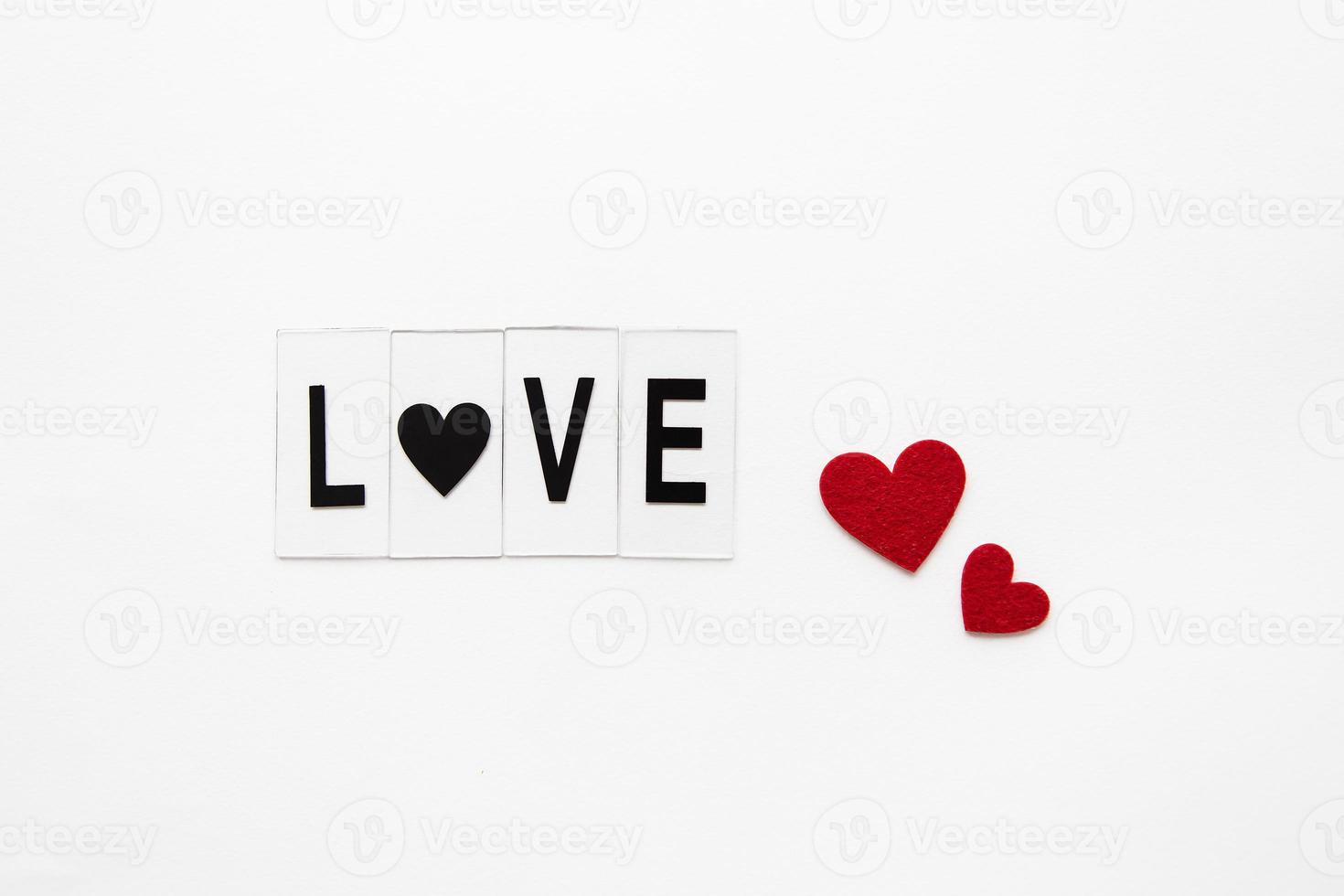 Beautiful inscription love on a white background, small red hearts. Postcard. photo