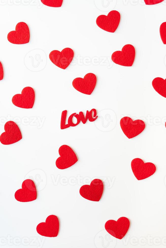 The background which consists of red hearts, the inscription love in the middle of the hearts. Vertical photo. Love concept, greeting card for valentine's day. photo