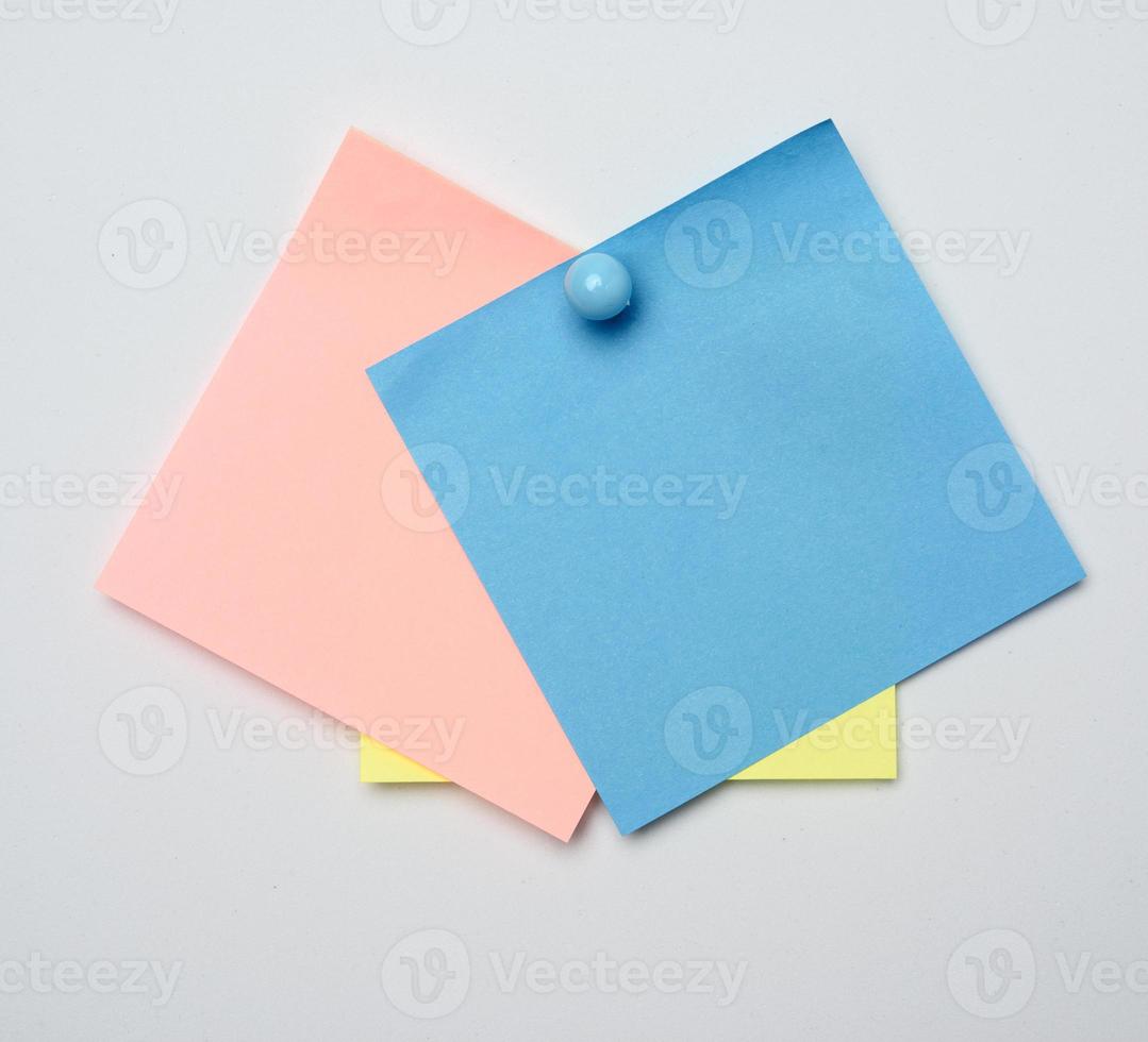 stack of colorful stickers pinned by blue button on white background photo